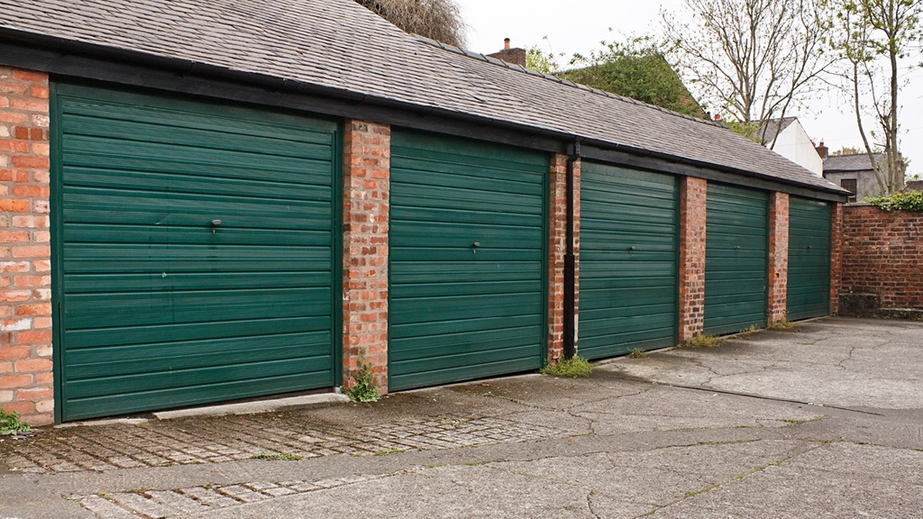 A block of five garages with dark green doors