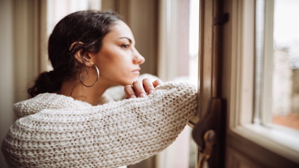 A young female looking deep in thought as she stares out a window.