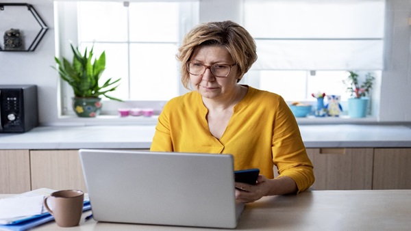 Woman sitting in a kitchen using her laptop