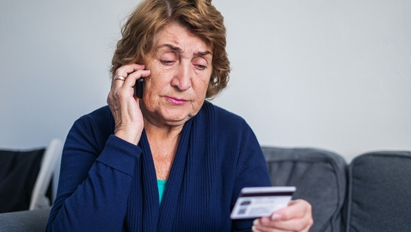 Older woman on mobile phone holding a credit card ready to make a payment